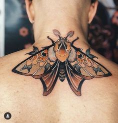 the back of a woman's neck with a moth tattoo on it