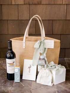 a bottle of wine sitting next to a gift bag and some other items on a table