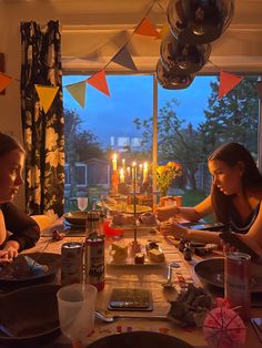 two women sitting at a table with candles in the middle and plates on the table