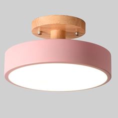 a pink ceiling light with wooden accents and dimmers on the top, hanging from a gray wall