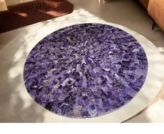 a round table with purple marble on it in a living room area next to a couch