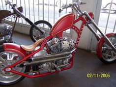 a red and silver motorcycle parked in a room next to another bike on the ground