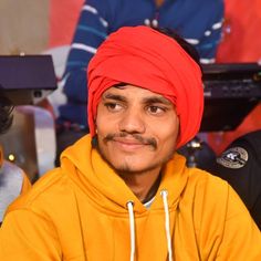 a man with a red turban sitting in front of other people