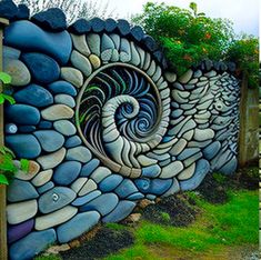 the side of a building with rocks painted on it and grass growing in front of it