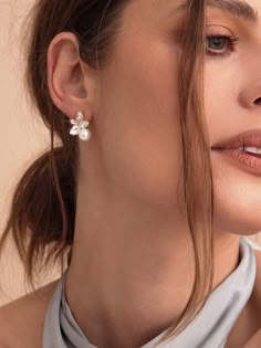 a close up of a person wearing a necklace and earring with flowers on it