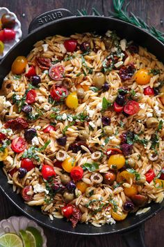 pasta salad with tomatoes, olives and feta cheese in a cast iron skillet