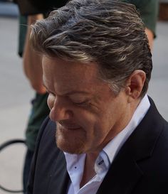 a close up of a person wearing a suit and holding a cell phone to his ear