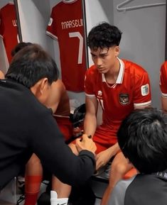 a group of young men sitting next to each other in front of a dressing room