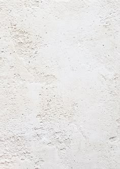 an orange and white cat laying on top of a bed next to a wall with peeling paint