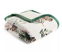 the blanket is white with green trim and has flowers on it, along with two matching blankets