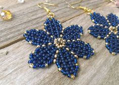 blue beaded flower earrings on wooden table next to beads and glass beads with gold accents