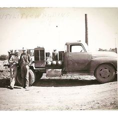 an old black and white photo of men standing in front of a truck with another man next to it