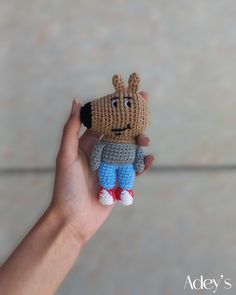 a hand holding a small crocheted stuffed animal in it's right hand