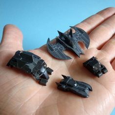 five pieces of black plastic in the palm of someone's hand, with bats on them