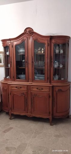 a wooden china cabinet with glass doors on the top and bottom, in a living room