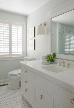 a white bathroom with two sinks, a toilet and a large mirror above the sink