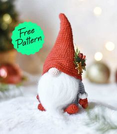 a small red and white gnome figurine sitting on top of a table next to a christmas tree