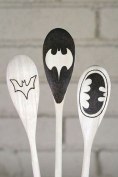 three wooden spoons with batman designs on them, one is black and the other is white