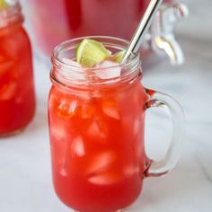 two mason jars filled with red liquid and lime wedges on the rim, sitting next to each other