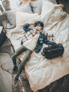 a woman laying on top of a bed next to a black handbag and purse