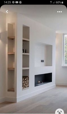 an empty living room with white walls and wood floors, fireplace in the center surrounded by bookshelves