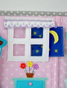 a close up of a doll house made out of fabric and felt with flowers on the window sill