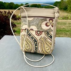 "A sweet  little bag specially made for all times where you need to have your phone(even the largest will fit)and a few other essentials . An excellent travel bag-it's flat and fits close to your body while leaving your hands free. Great for shopping,dancing or carrying a baby on your arm. Chenille Tapestry imported from Turkey combined with Cream Color Leather. A long adjustable Leather Strap. 6 \"Zipper Top opens to 1 large section with a small pocket that could hold a few credit card, plus a Portable Beige Shoulder Bag For Everyday Use, Beige Pouch Shoulder Bag With Mobile Phone Pocket, Beige Pouch Phone Bag For Daily Use, Everyday Beige Pouch With Cell Phone Pocket, Small Portable Bags For Daily Use, Cream Rectangular Phone Bag For Daily Use, Cream Rectangular Pouch For Travel, Beige Mobile Phone Bag For Everyday Use, Rectangular Cream Pouch For Travel