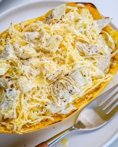 a white plate topped with spaghetti and cheese next to a silver fork on top of a table