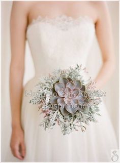 a woman in a wedding dress holding a succulent bouquet