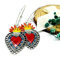 Our sizzling Mexican sacred heart earrings with rhinestones are sure to turn heads! Featuring gorgeous hand-decorated bohemian patterns, each earring will make you look alluring and elegant. From eye-catching glittering enamel paint to charming silver details, you'll feel like a glamorous diva! These earrings make the perfect Valentine's present for her or a great way to pamper yourself. Show your love and make a bold statement! Style: Bohemian Mexico Folk ArtMaterial: Silver tone Metal AlloyCol Luxury Heart Earrings For Valentine's Day, Luxury Romantic Heart Earrings For Women, Luxury Red Bohemian Earrings, Mexican Flag Jewelry, Mexican Filigree Heart Dangle Earrings, Valentines Presents For Her, Valentines Presents, Present For Her, Hand Painted Earrings