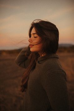 a woman standing in a field with her eyes closed