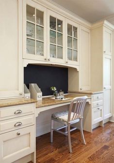 a kitchen with white cabinets and wooden floors, including a computer desk in the center