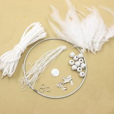 white feathers, beads and other items are laid out on a beige surface with scissors