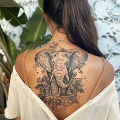 an elephant tattoo on the back of a woman's shoulder