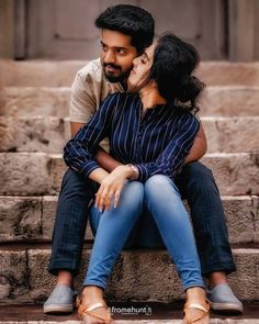 a man and woman are sitting on some steps together, one is kissing the other's forehead