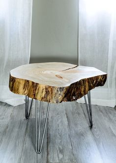 a wooden table with hairpin legs in front of a white wall and curtains behind it