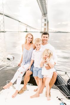 a family sitting on the back of a boat in front of a bridge and water