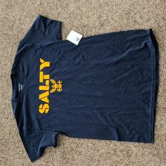 Us Navy Salty T-Shirt - Navy/Yellow. Size Medium. New With Tags Casual Yellow Shirt With Logo Print, Yellow Pre-shrunk Tops For Fan Merchandise, Yellow Crew Neck Fan Apparel Top, Yellow Pre-shrunk Tops For School Spirit, Casual Yellow Shirt With Letter Print, Yellow Logo Print Top For Fans, Yellow Fan Apparel Tops For Streetwear, Yellow Logo Print Tops For Fan Merchandise, Yellow Graphic Print Top For School Spirit