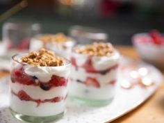 three desserts with strawberries and whipped cream in them on a tray, ready to be eaten