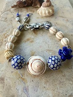 Boho beach vibes with this coastal Islander bracelet. Large conch shell pendant set in with two blue and white ceramic beads, blue ceramic turtle on the side with 3 African beads, vintage Islander howlite stones with a silver flower clasp, ending off with silver seed bead tassel.  8 inches long Nautical Style Blue Bracelets For Beach, Handmade Nautical Bracelets For Beach, Handmade Nautical Style Bracelets For Beach, Blue Shell Jewelry For Beach Season, Blue Nautical Jewelry For Beach, Blue Shell Bohemian Bracelets, Bohemian Blue Shell Bracelets, Bohemian Blue Shell Bracelet, Ceramic Turtle