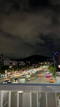 a city street filled with lots of traffic under a dark cloudy sky at night time