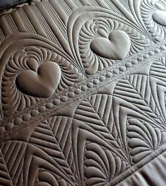 a close up view of a quilted surface with heart shapes on the edges and an intricate design