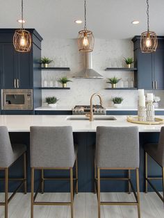 a kitchen with blue cabinets and white counter tops, gold accents and pendant lights over the island