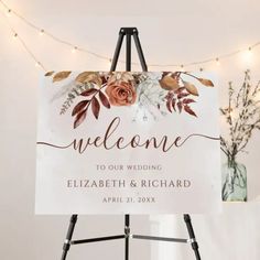 an easel with a sign that says welcome to our wedding and flowers on it