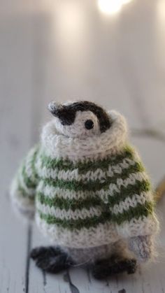 a small knitted penguin sitting on top of a wooden table