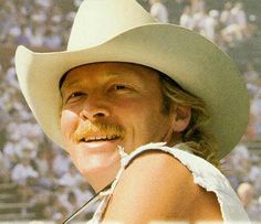 a man wearing a white cowboy hat and holding a baseball bat in his right hand