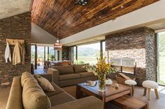 a living room filled with furniture next to a stone wall covered in wood planks