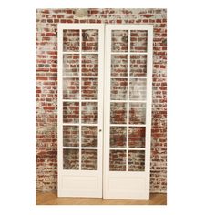 two white double doors in front of a brick wall with glass panels on each side