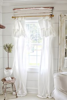 a window with white curtains and a potted plant