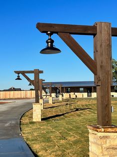 a bell on top of a wooden pole in front of a building with grass and trees